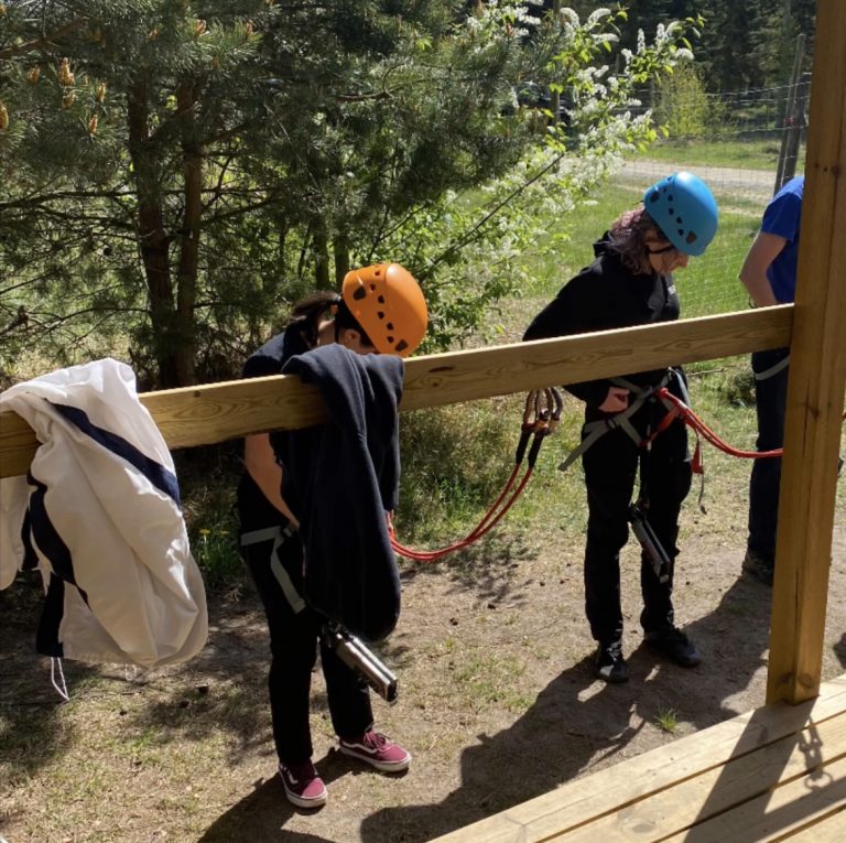 Två elever monterar selar inför klättring längs höghöjdsbana.