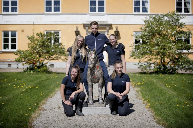 Flyinges mangårdsbyggnad med fem elever runt en hästskulptur