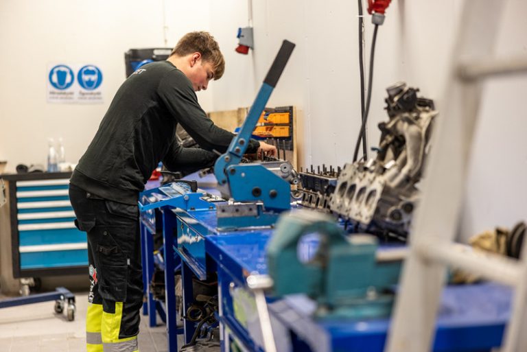  En elev från Fordons- och transportprogrammet står och meckar med en motor.