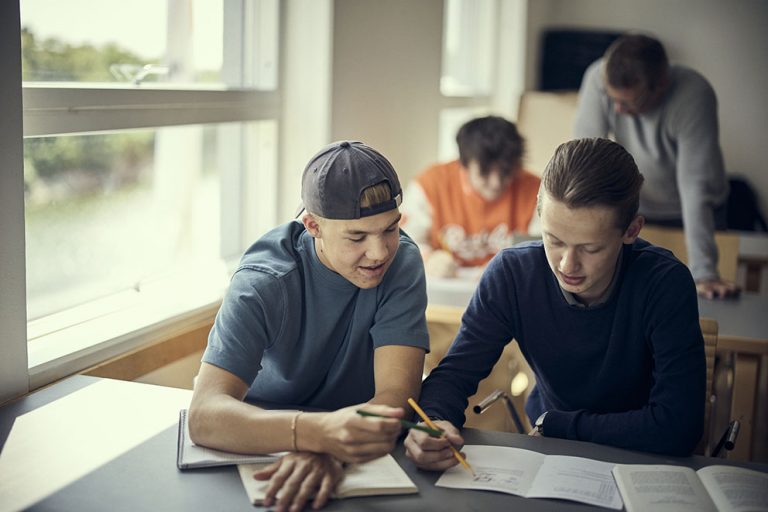 Tre elever och en lärare i ett klassrum.