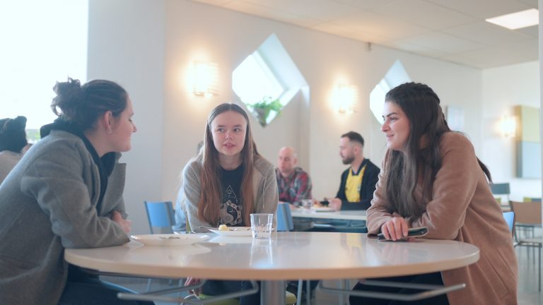 Några elever sitter vid ett bord i matsalen och njuter av en pedagogisk frukost.