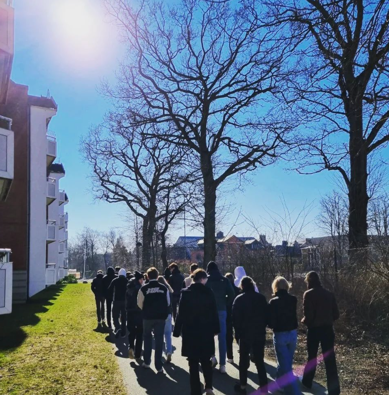 Elever tar en pedagogisk promenad tillsammans med sin lärare utomhus.