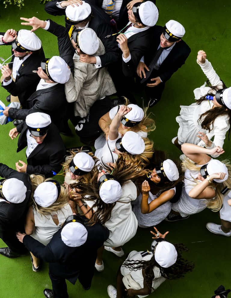 Elever och studenthattar sedda uppifrån med glada studenter under utspringet.