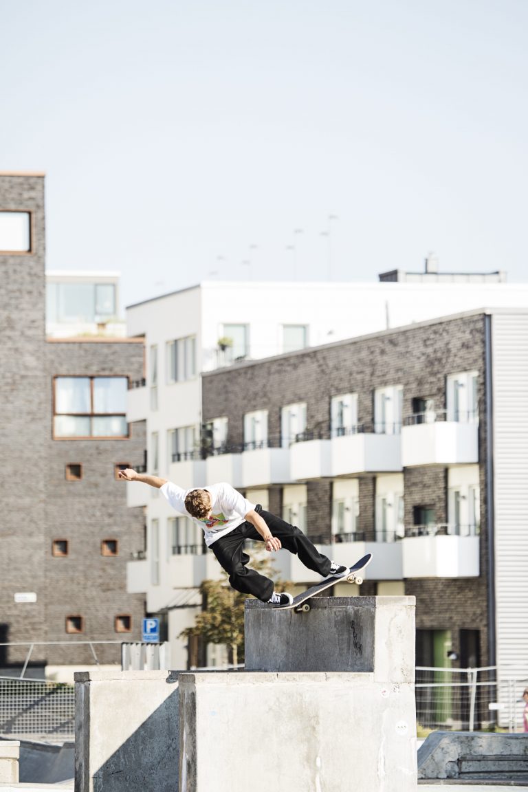 Skateboardåkare i stadsmiljö mitt i ett trick.