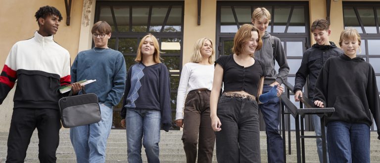 En grupp elever går ner för trappan utanför en skolbyggnad.