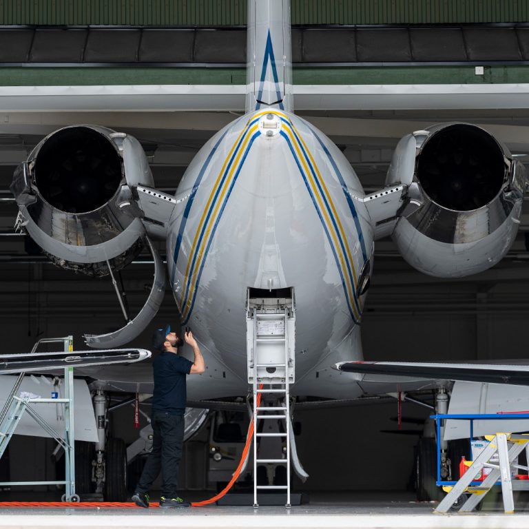 Eleven står under bakdelen av flygmaskinen och lyser med en ficklampa i utförandet av en pre-flight inspektion.