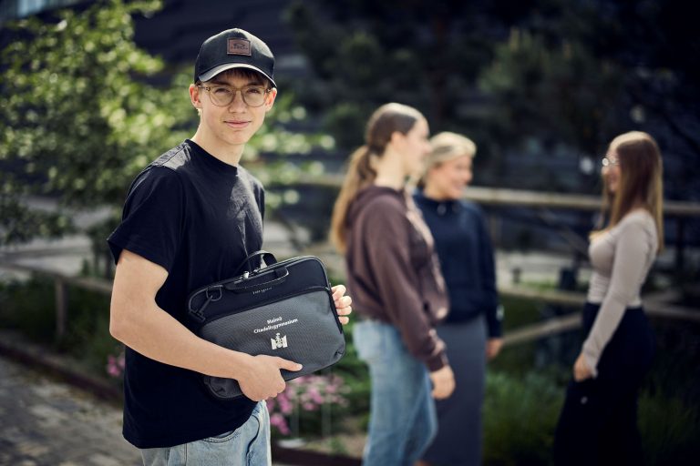 Glada elever utanför skolan med skolväska. 