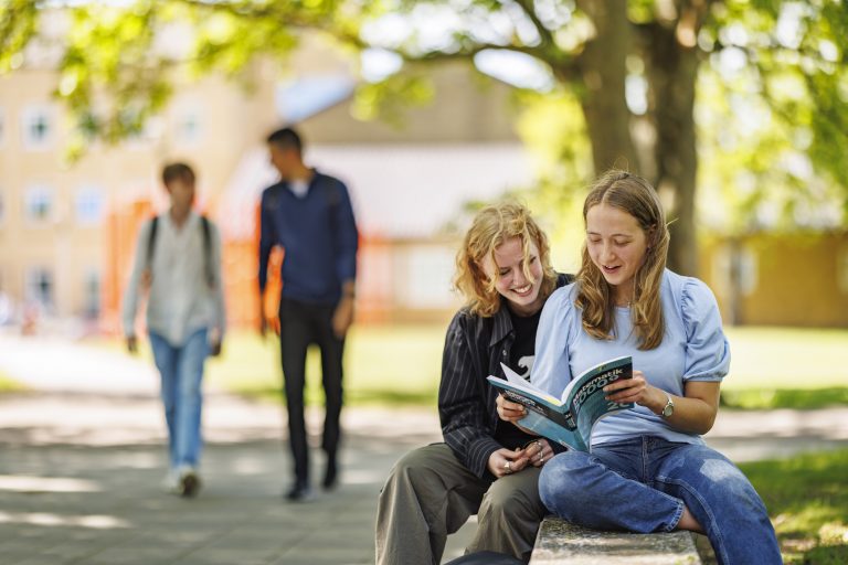 Glada elever umgås i grön och fin miljö utanför skolan.