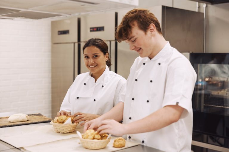 Två elever lägger upp bröd i metodköket där undervisningen sker på restaurangprogrammet.