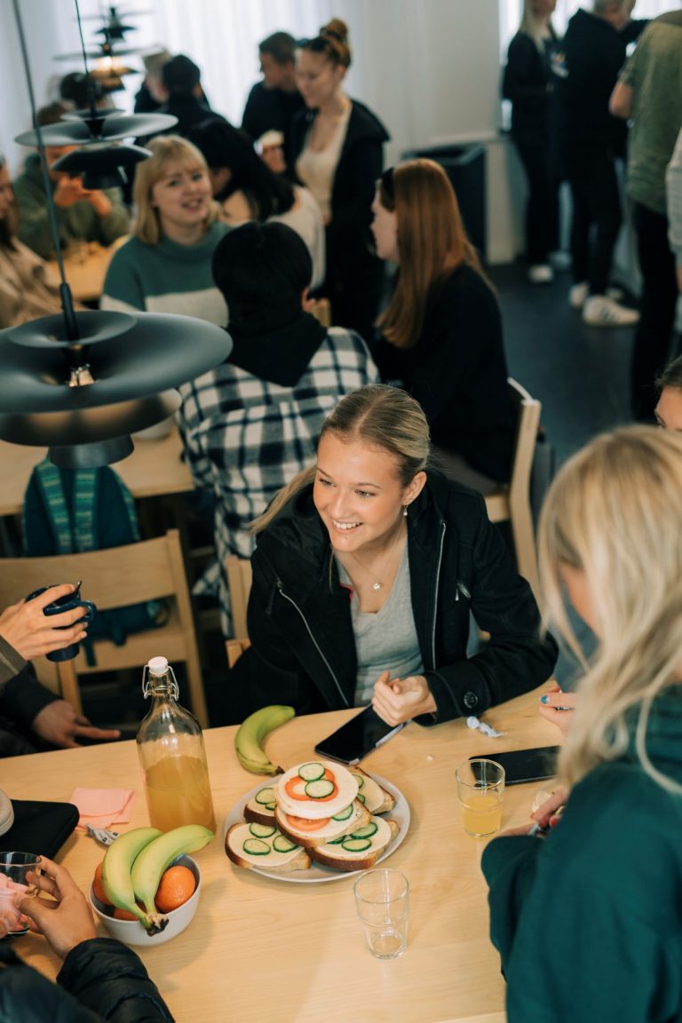 Elever i en matsal med frukt och smörgåsar på bordet i vår breakfast club.