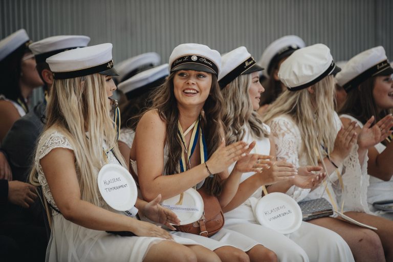 Studentbild på glada studenter sittande på ett podium.