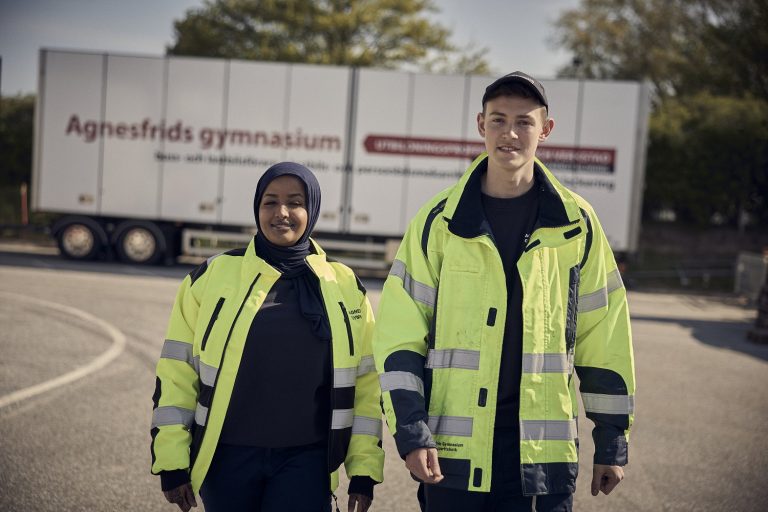 Två glada elever framför skolans lastbil