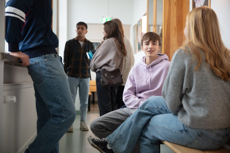 Rast och några elever sitter i korridoren, pratar och chillar.