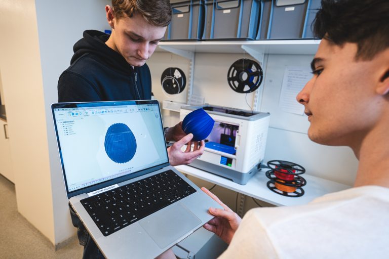 Två elever kontrollerar resultatet i 3D-skrivaren.