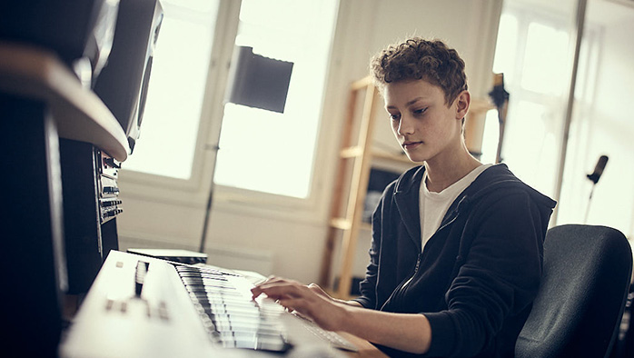 Elev producerar musik framför en keyboard.