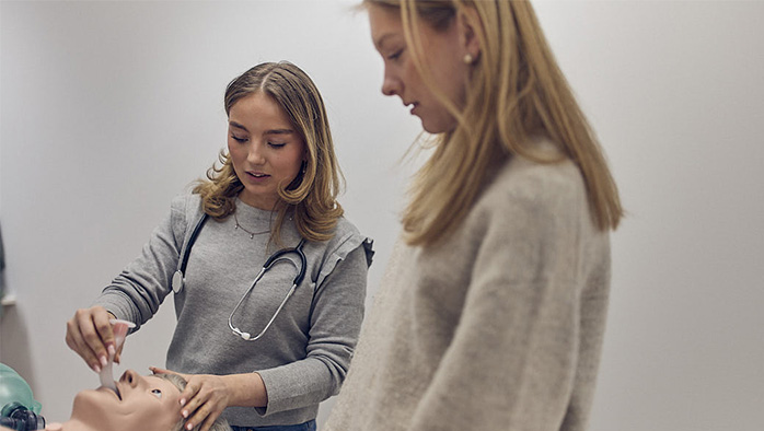 Två elever i ett klassrum som övar intubering på en testdocka.