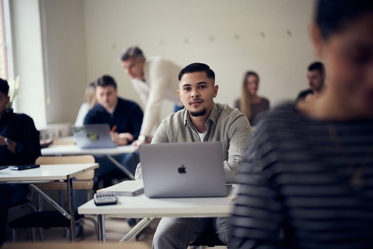 Elev i ett klassrum med laptop framför sig.