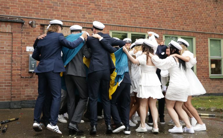 Elever som står i ring och kramas och firar studenten.