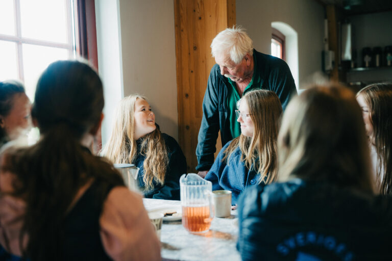Elever och lärare i samtal under fikapaus i matsalen.