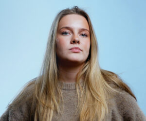 Porträtt av ung person mot ljusblå bakgrund