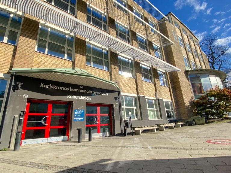 Entré till Törnströmska gymnasiet med röda dörrar och skylt ovanför ingången. 