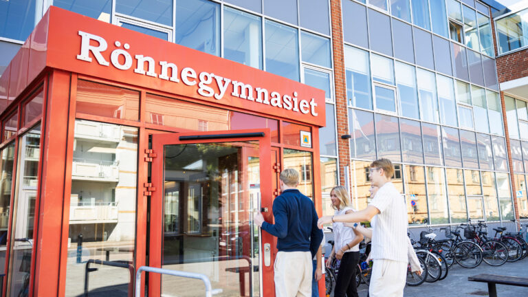 Tre elever går in via skolans entré. 
