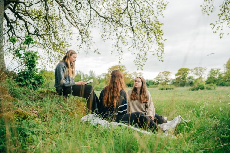 Tre elever umgås och pluggar i naturen nedanför vårt studentboende