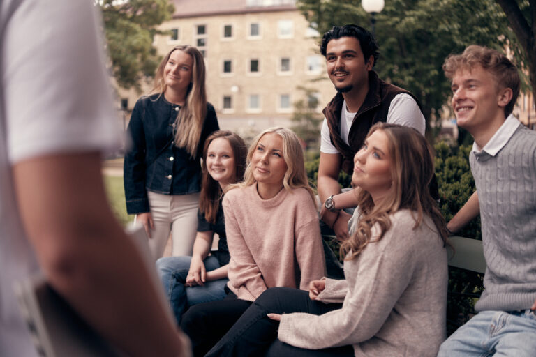 Elever som sitter i parken utanför skolan och umgås.