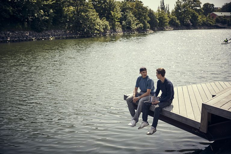 Två elever sitter på bryggan utanför Malmö Neptunigymnasium