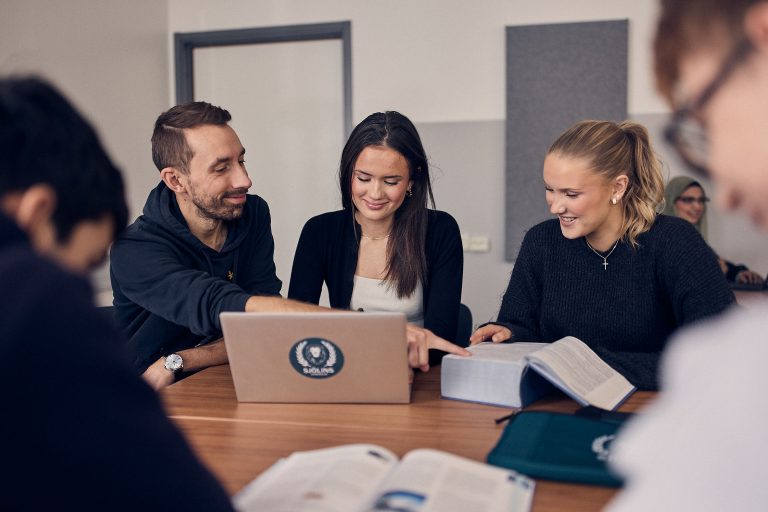 Intresserade elever sitter med lärare i klassrummet och får hjälp med sina juridikstudier.