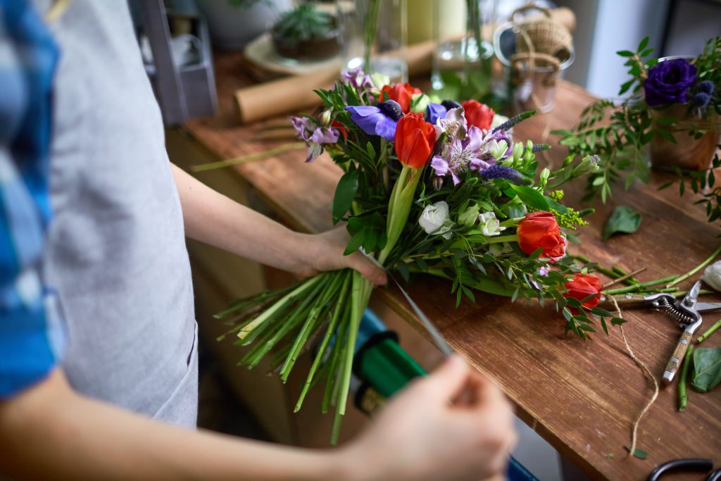 Floristen knyter band på en blombukett i blandade färger